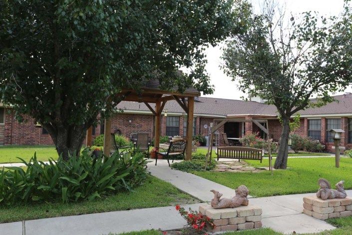 A peaceful garden with a gazebo and pathway surrounded by trees.
