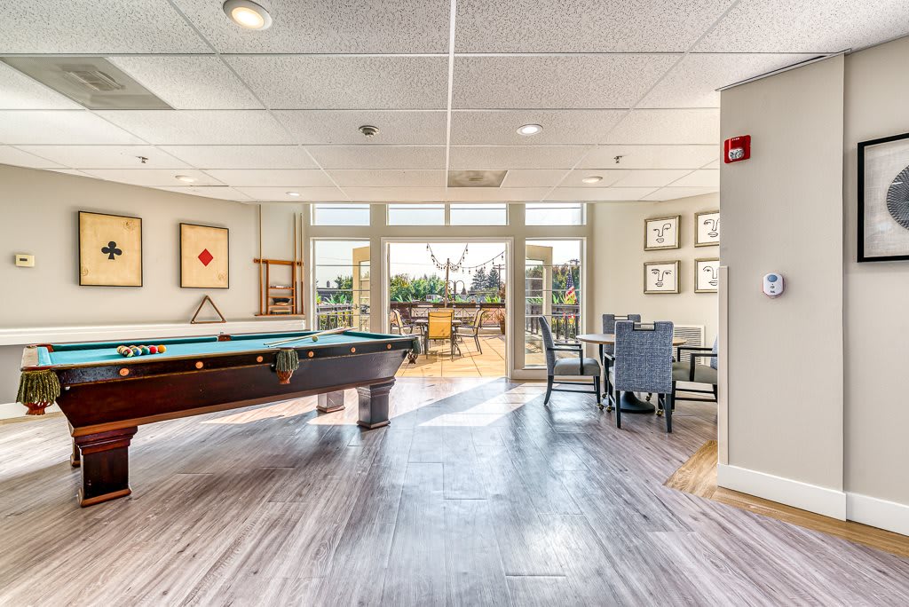 A modern game room featuring a pool table and seating area with abundant natural light.