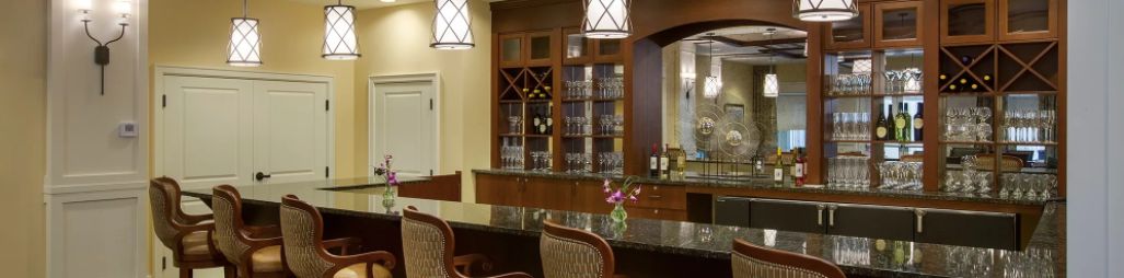 A cozy bar area with wooden cabinetry and wine glasses displayed.