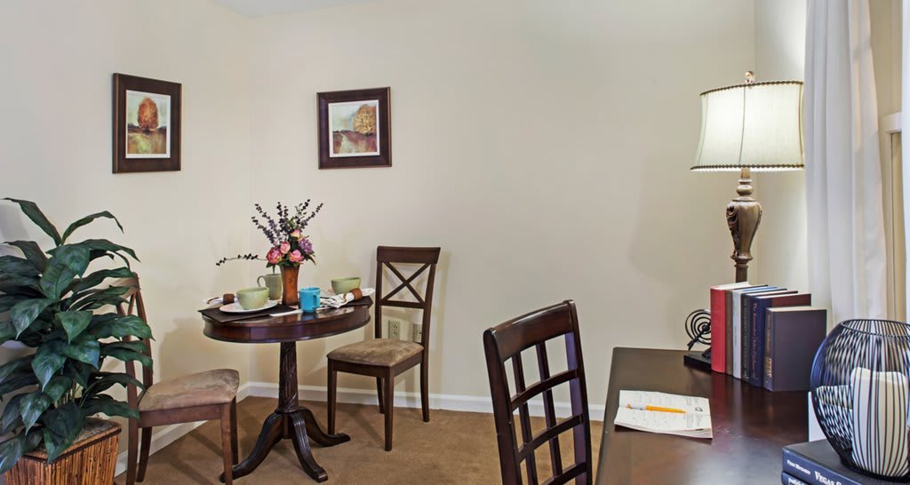 A cozy dining area with a round table and chairs, adorned with flowers and wall art.