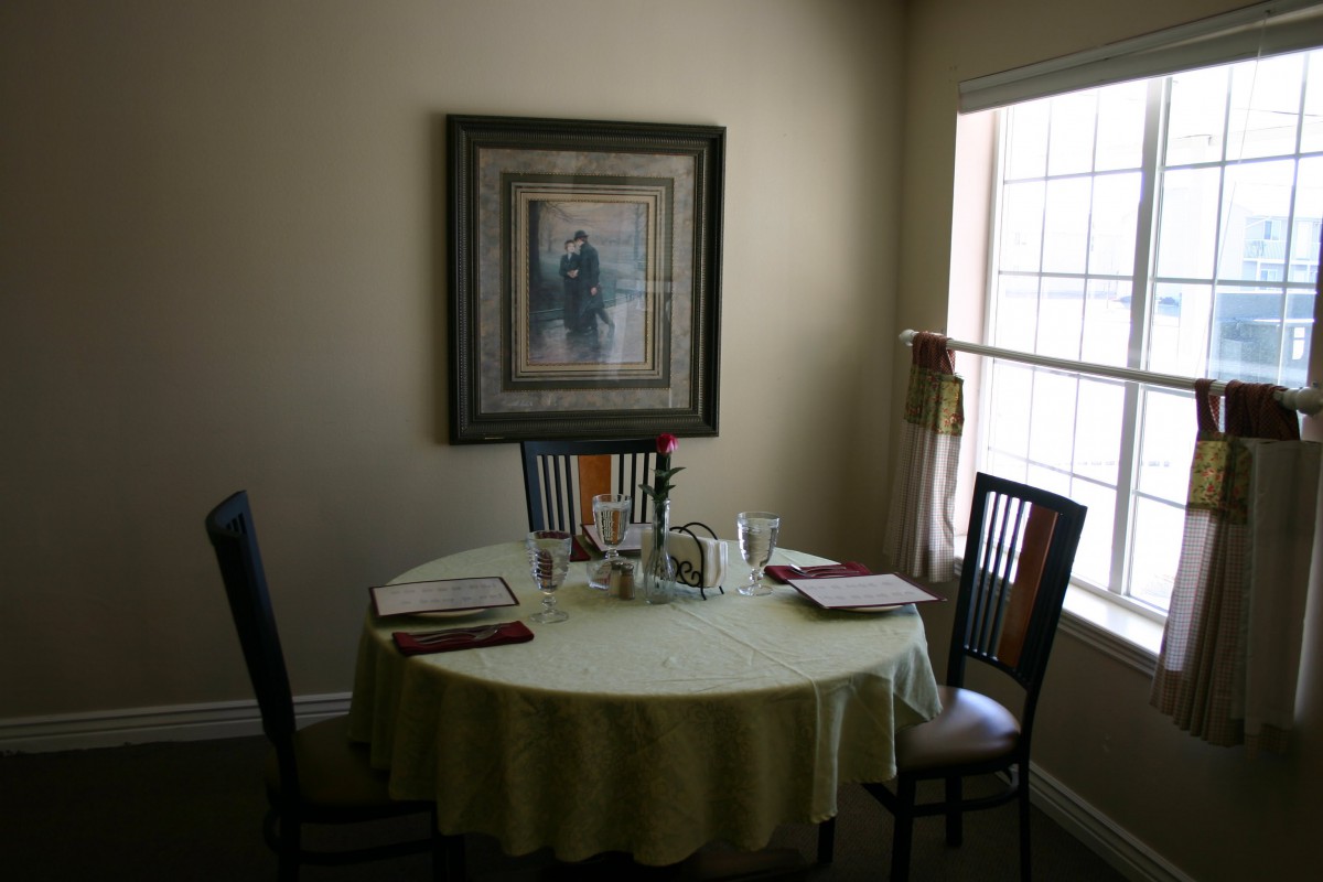 A cozy dining room with a round table and chairs by a window.