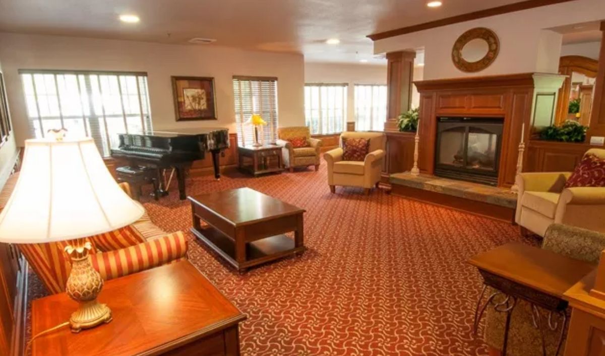 A cozy living room featuring a fireplace, a grand piano, and comfortable seating.