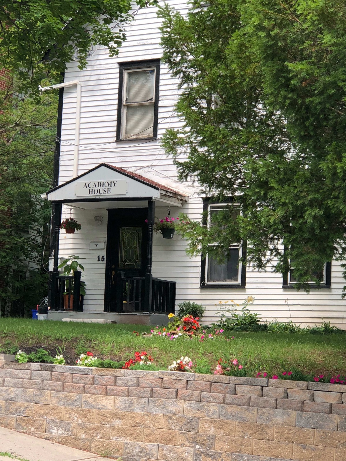 A quaint two-story house with a small garden in the front yard.