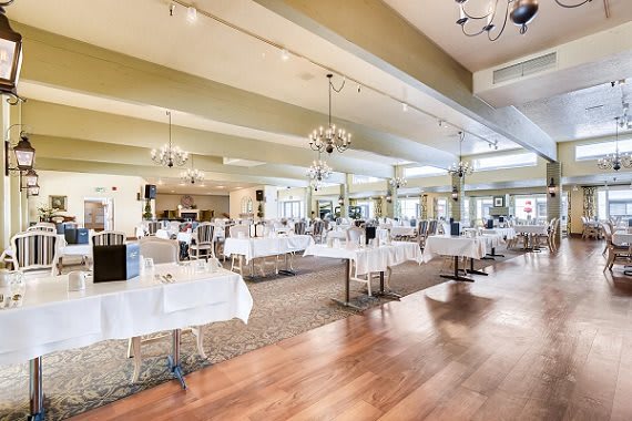 A spacious and elegant restaurant interior with neatly arranged tables and chandeliers.