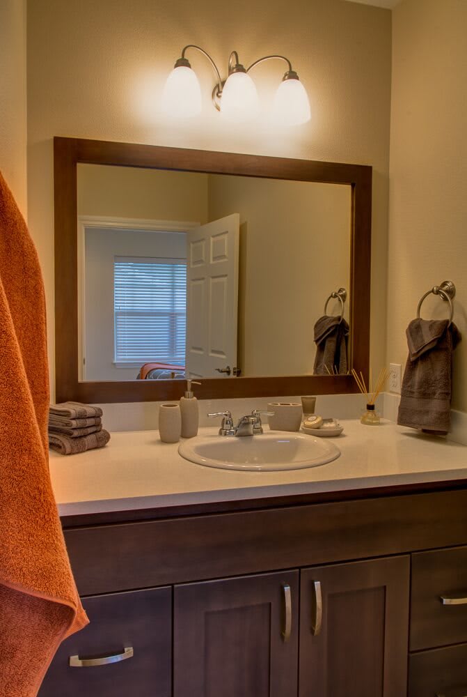 A tidy bathroom with a large mirror above the sink and neatly arranged towels.