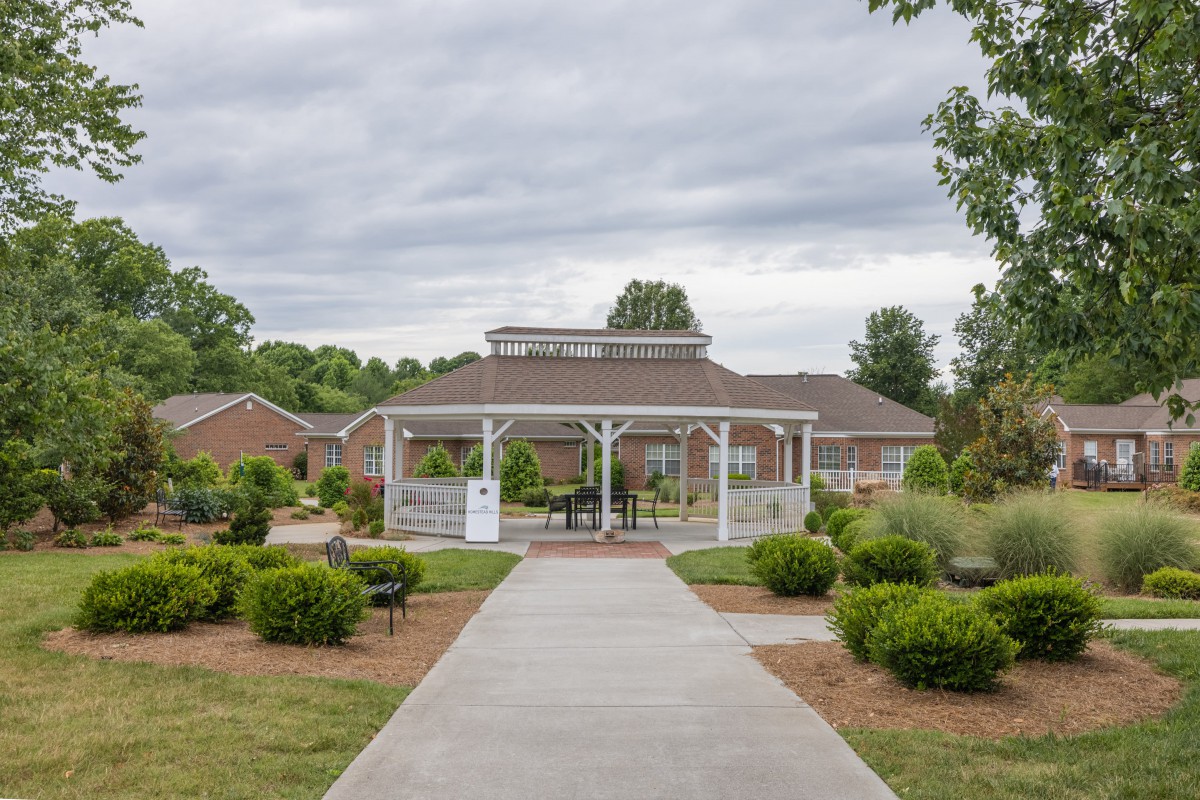 A landscaped garden leads to a building with a gazebo structure in front.