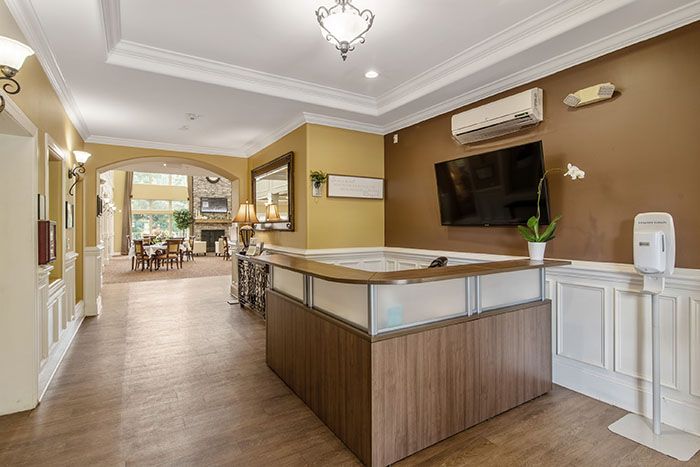 A modern reception area featuring a wooden desk, television, and elegant lighting.