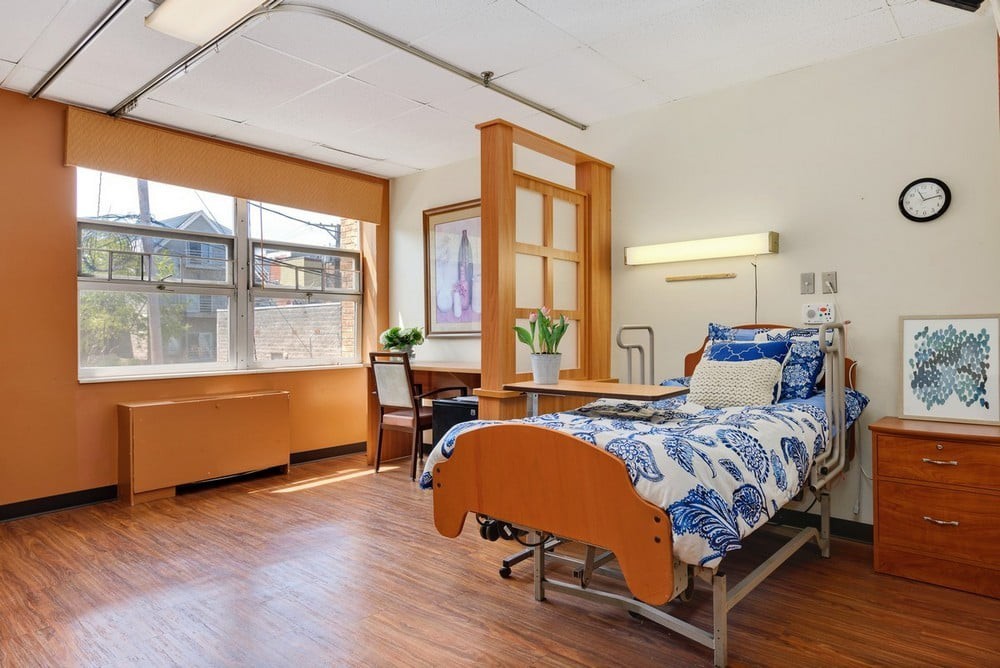 A clean and well-lit hospital room with a single bed and large window.