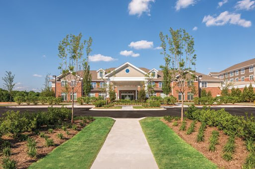 A beautifully landscaped residential building under a clear blue sky.