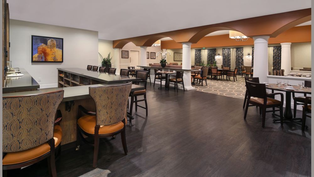 A spacious restaurant interior featuring a blend of modern and classic design elements, with a dining and bar area.