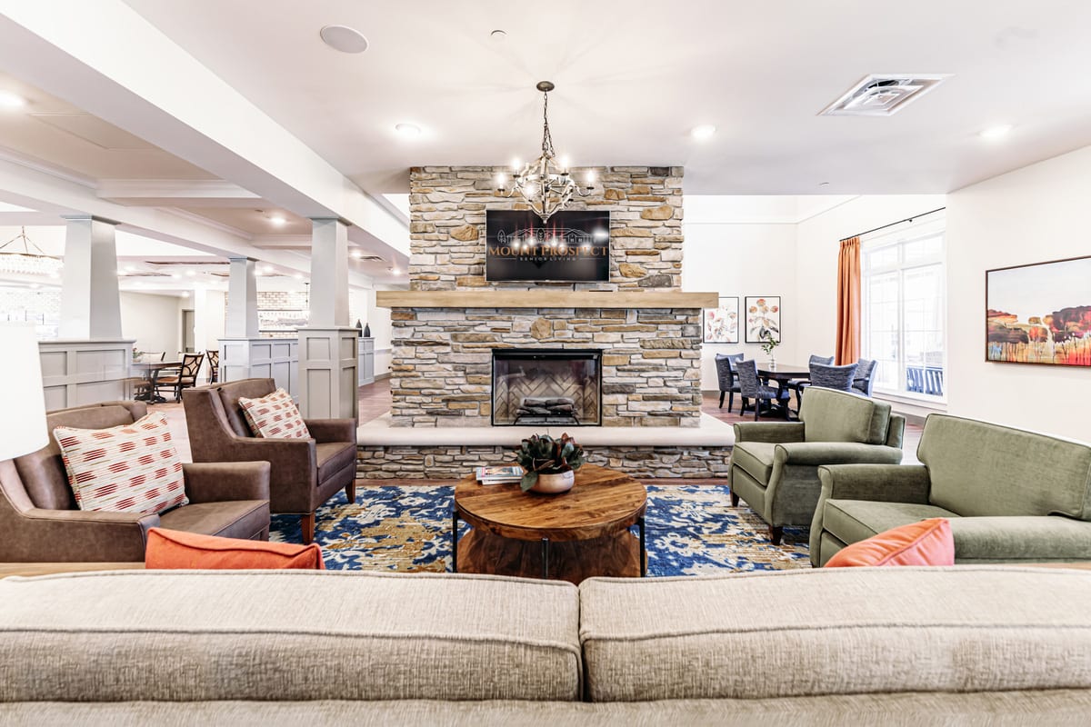 A cozy living room featuring a stone fireplace, modern seating, and elegant chandelier.