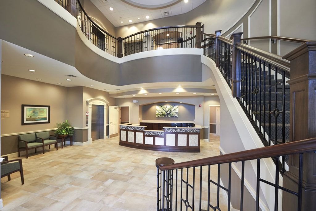 A modern lobby with a reception desk and a grand staircase.