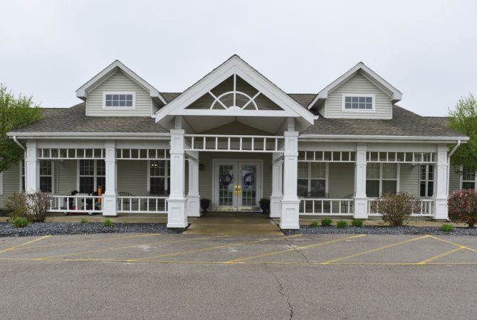 A white house with a distinctive porch and several windows.
