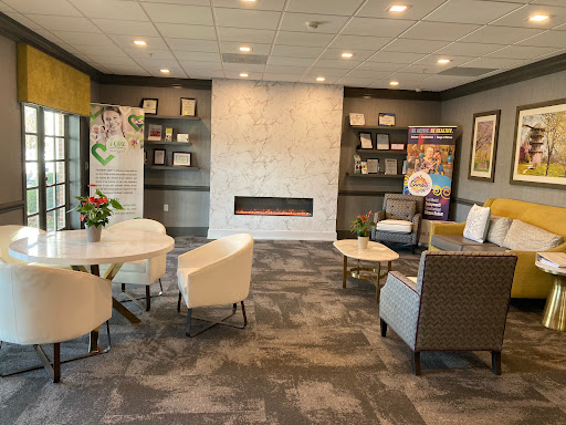 A comfortable and modern lounge area featuring a cozy fireplace, stylish seating arrangements, and decorative shelves.