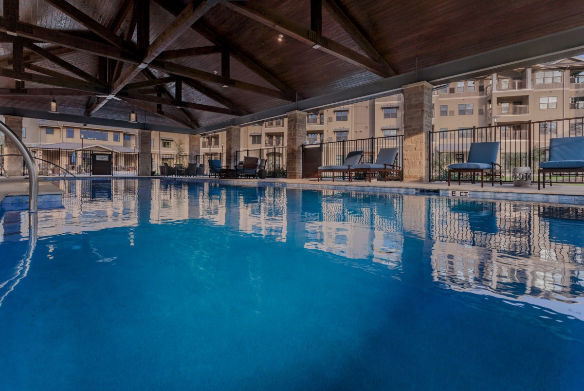 A spacious indoor swimming pool with lounge chairs lining the deck, providing a serene space for relaxation.