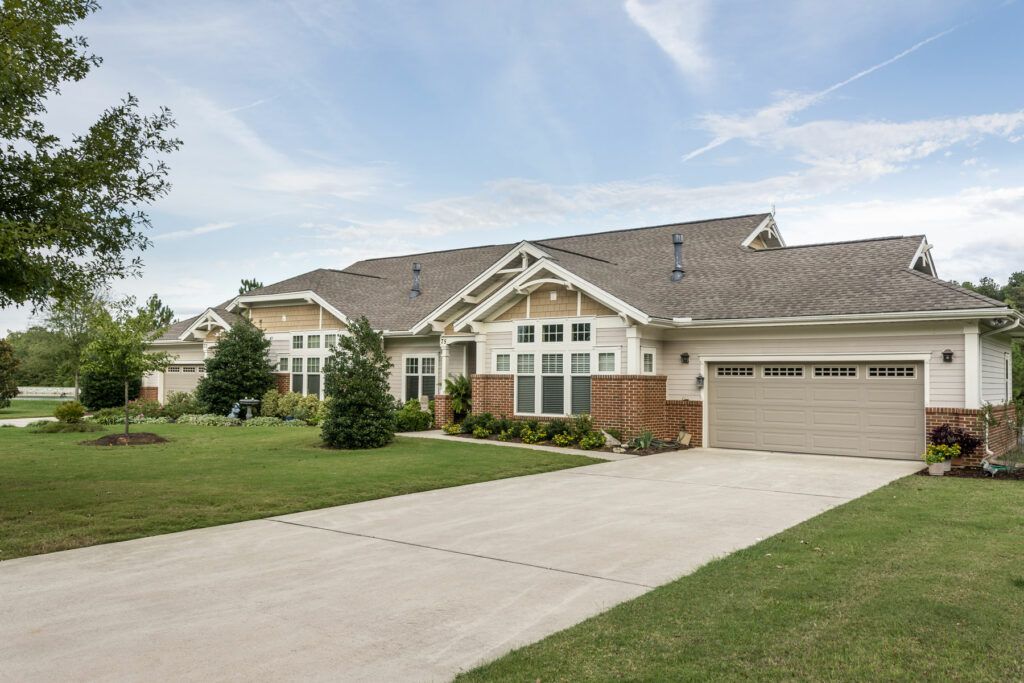 A suburban house with a large driveway and well-maintained lawn.