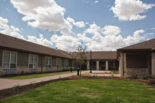A serene view of a modern building surrounded by lush greenery and a partly cloudy sky.