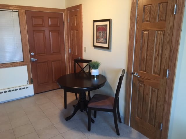 A cozy corner with a small table and two chairs, complemented by a potted plant and wall art.