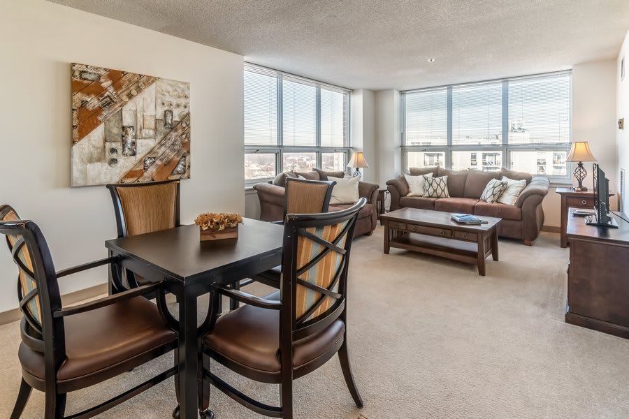 A spacious living and dining area with large windows that allow natural light to fill the modern, well-furnished apartment.