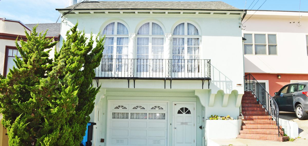 A white house with a garage and arched windows above.