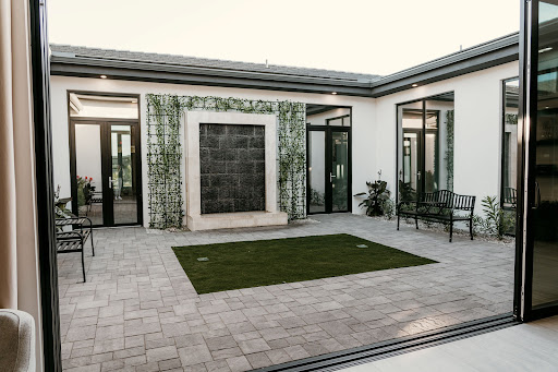 A contemporary courtyard featuring a stylish water wall, modern patio furniture, and lush greenery.