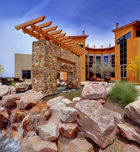 Outdoor view of a modern building with stone features and a water element.
