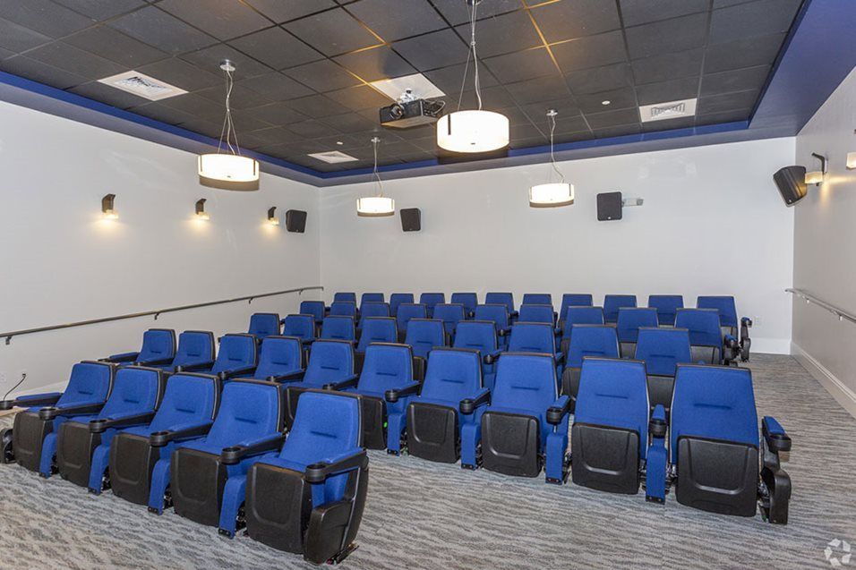 An empty theater room with rows of blue seats.