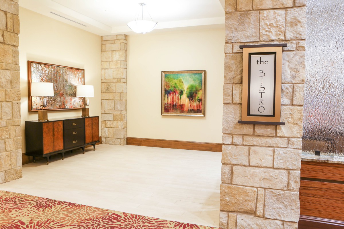 A well-lit lobby area with stone walls, featuring artwork and stylish furniture.