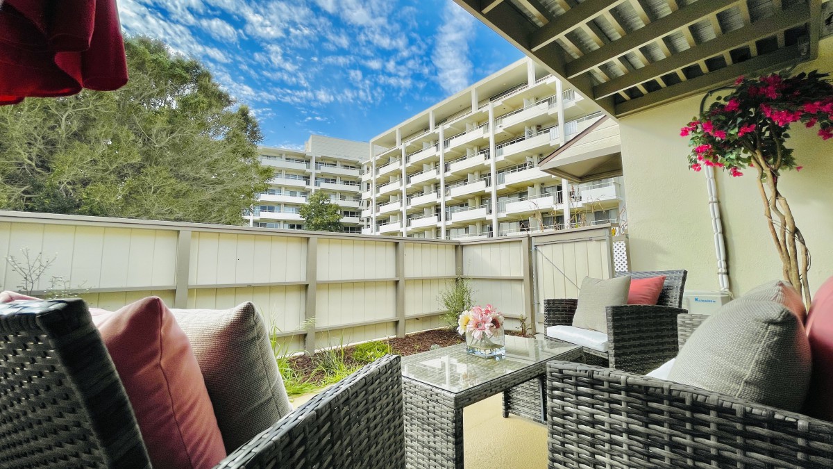 A cozy patio with wicker furniture overlooks a modern apartment building.