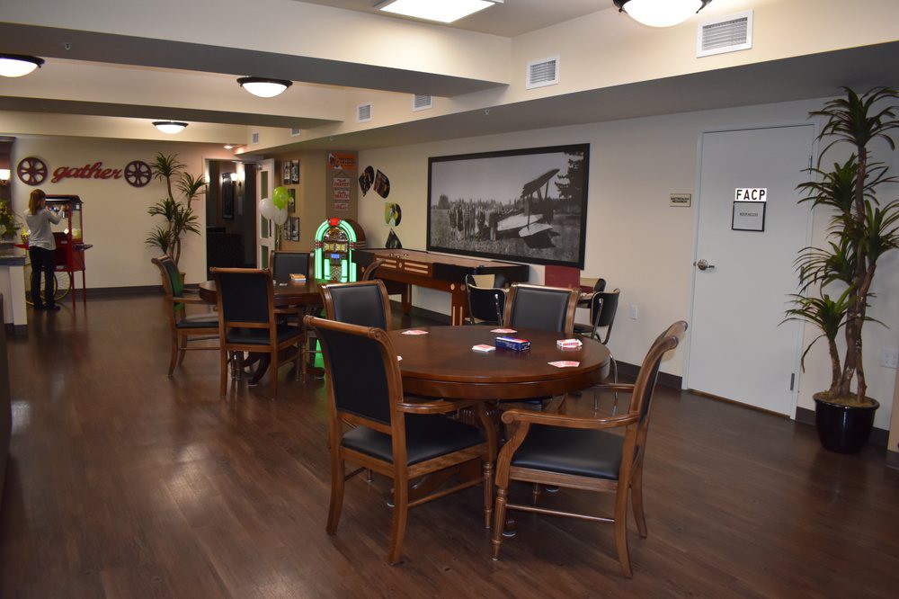 A cozy lounge area with tables, chairs, a jukebox, and wall decor.