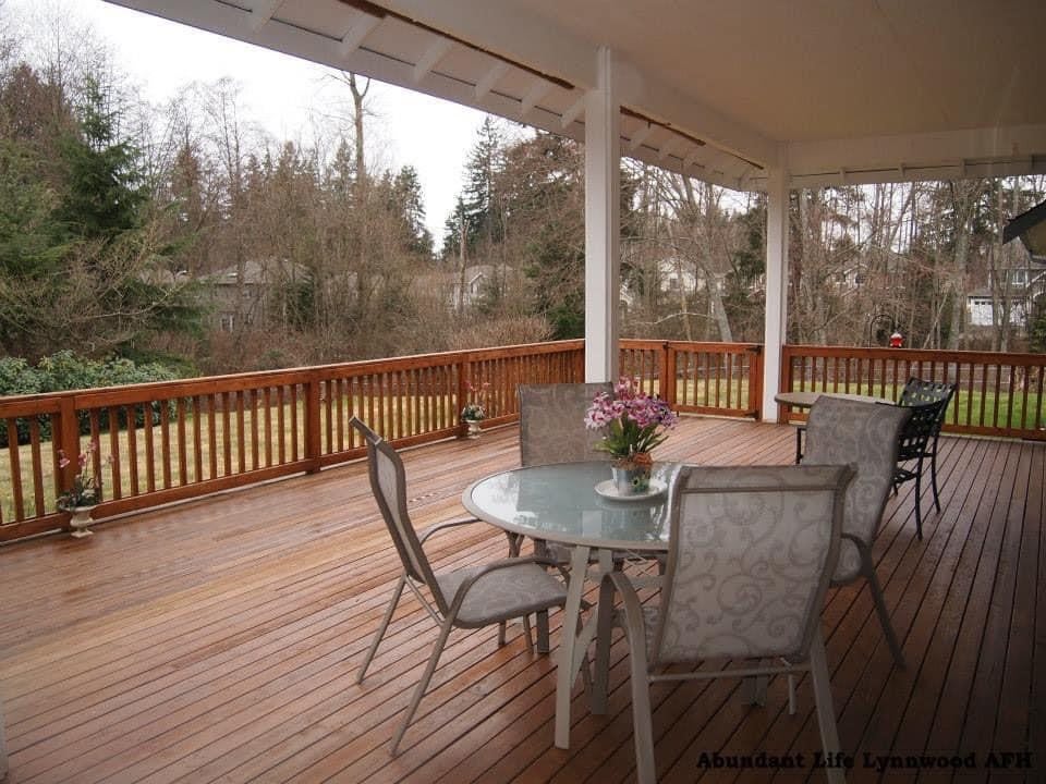 A spacious wooden deck with a table and chairs, surrounded by nature.