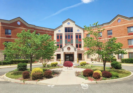 A modern educational institution surrounded by vibrant landscaping under a clear blue sky.