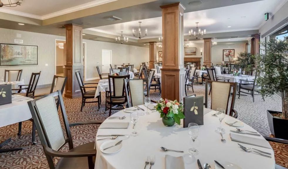 An elegantly arranged banquet hall with round tables and formal table settings.