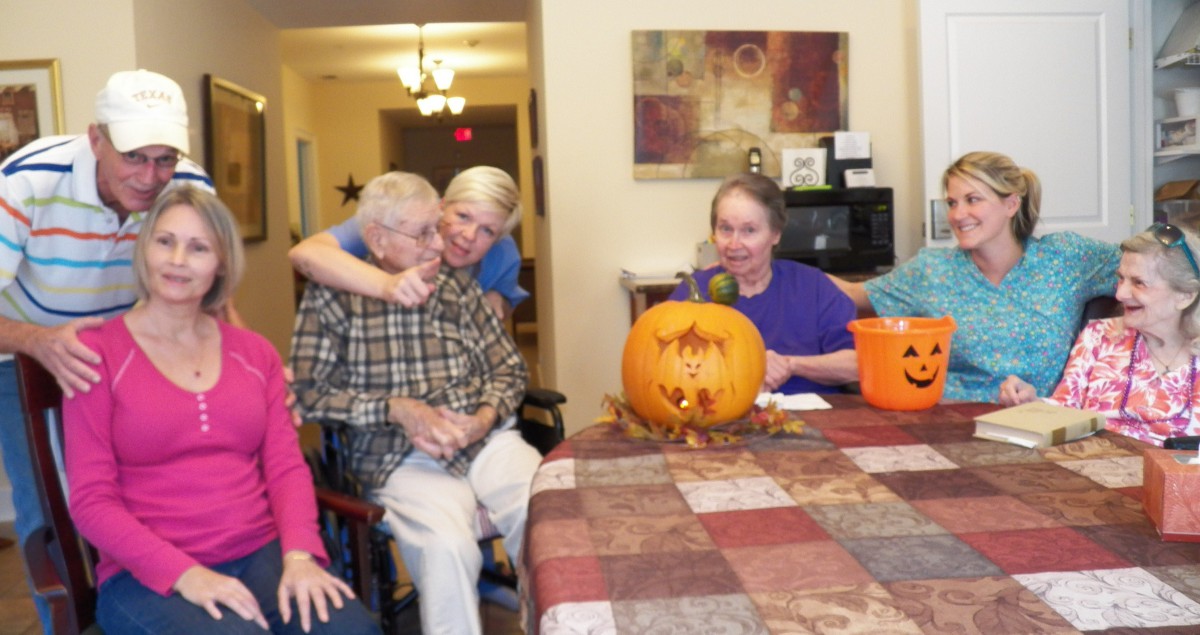 A group of people enjoying pumpkin carving together indoors.