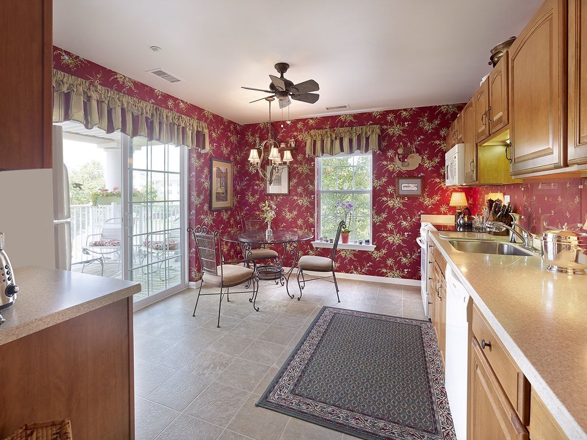 Cozy kitchen with red floral wallpaper and natural lighting.