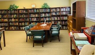 A quiet library reading room with a table and chairs surrounded by bookshelves.