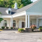 A building with a covered entrance featuring columns and surrounding landscaping.