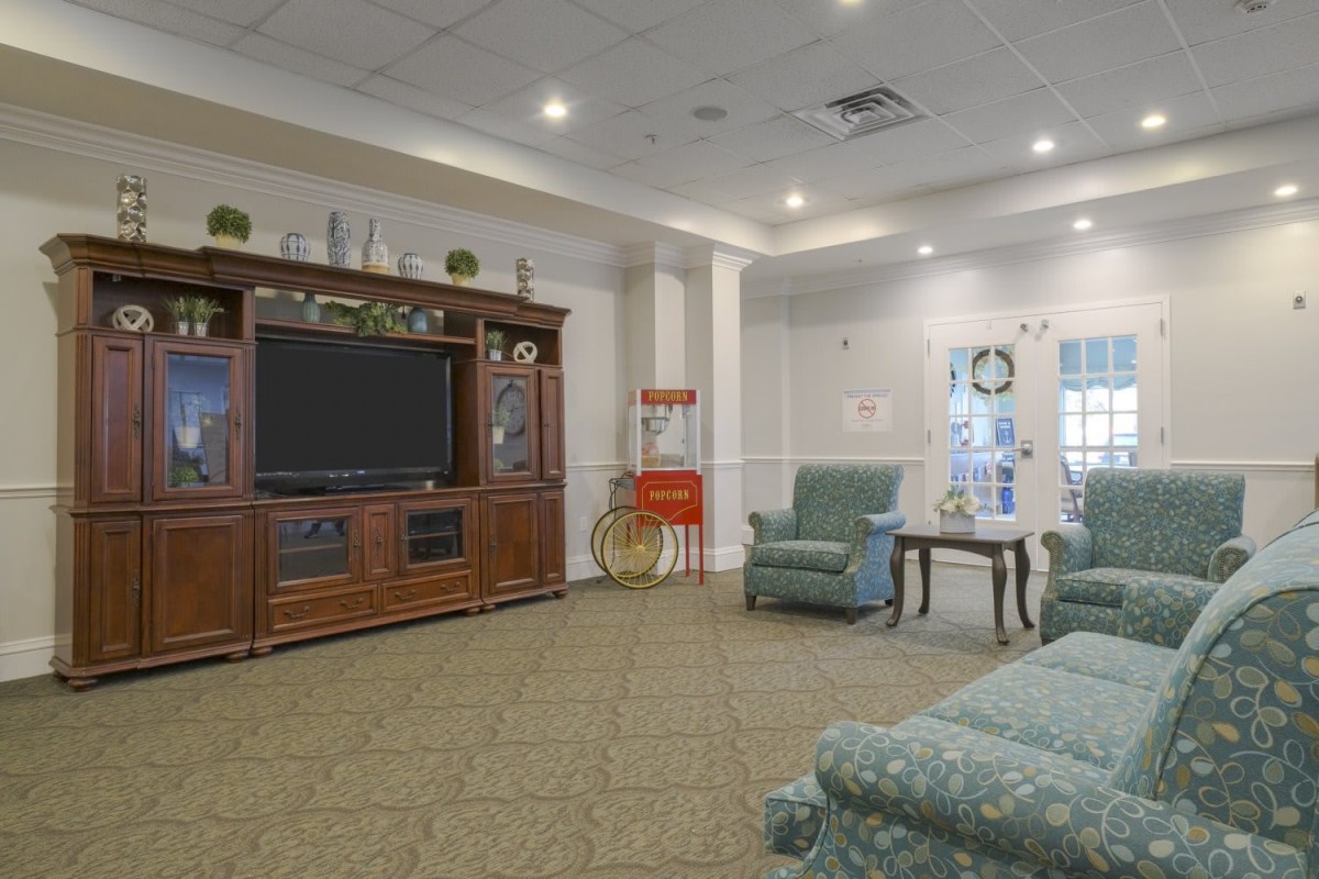 A cozy living room with armchairs, a large television, and tasteful decor.