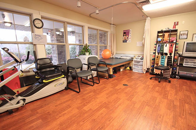 A bright and well-equipped physical therapy room with various rehabilitation tools and exercise equipment.