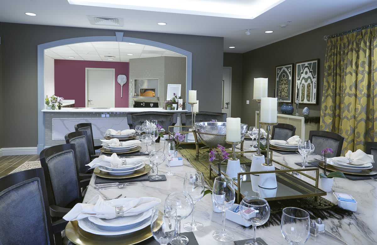 An elegantly set dining table with candles and fine dinnerware in a modern dining room.