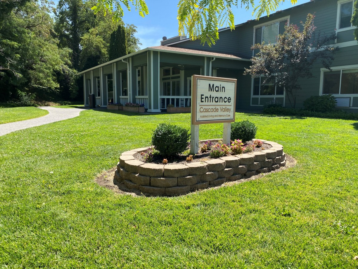 A building with a landscaped entrance featuring a sign for the main entrance of a clinic.