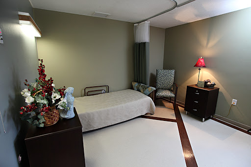 A serene and minimalistic bedroom featuring a bed, chair, and soft decorative elements.