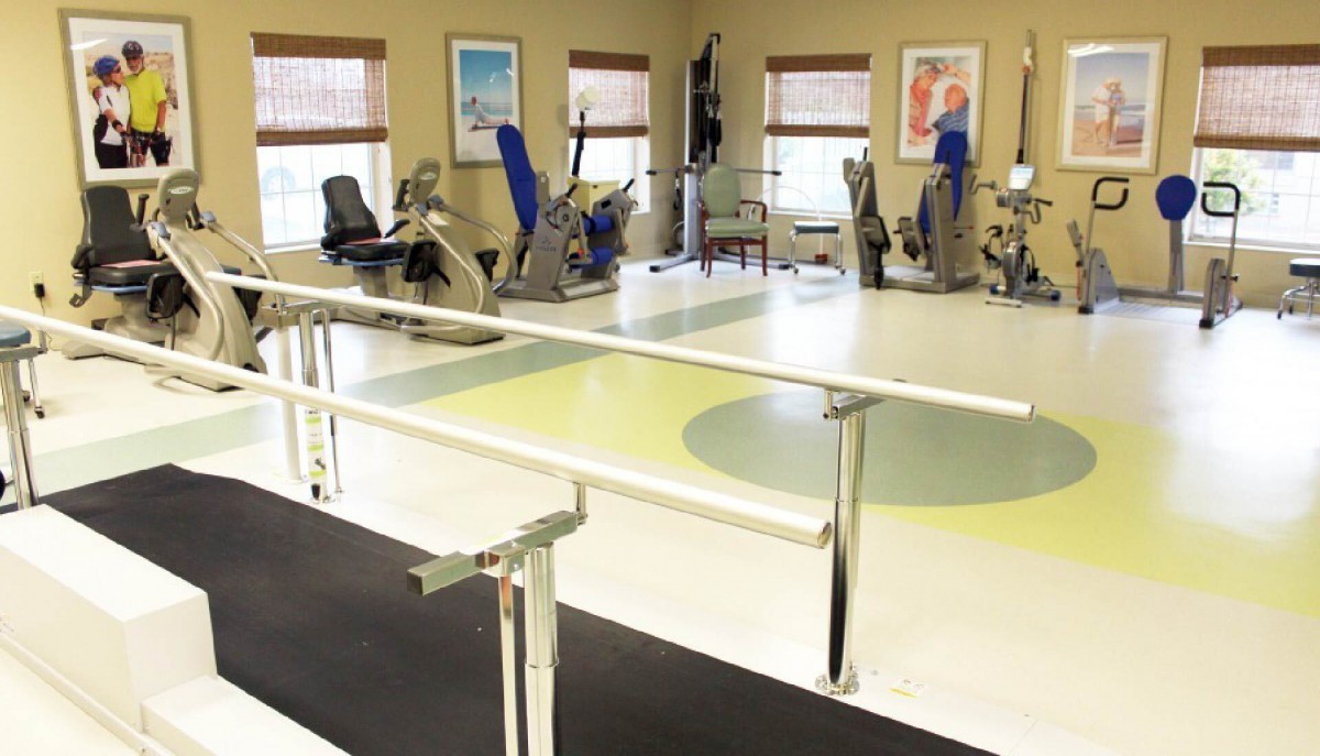 A physical therapy room equipped with exercise machines and parallel bars for rehabilitation exercises.