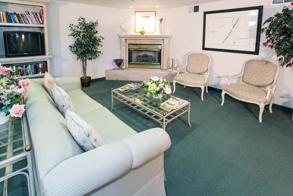 A cozy living room with a fireplace, featuring a sofa, armchairs, a coffee table, and elegant decor.