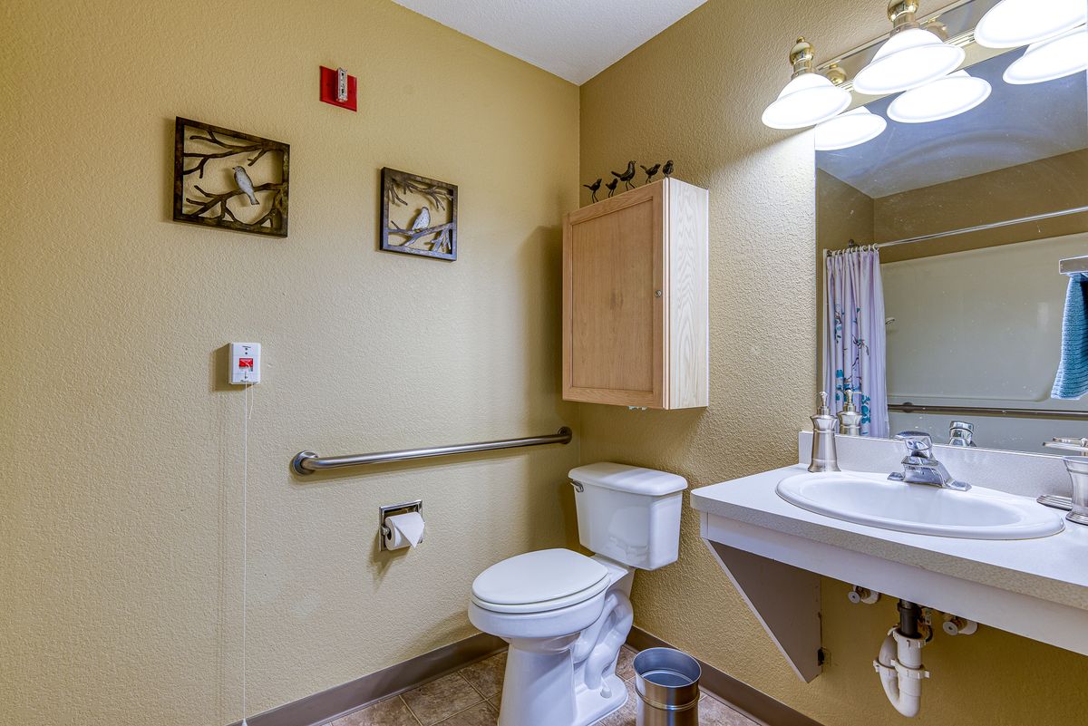 A bathroom featuring a toilet, sink, and decorative wall art.