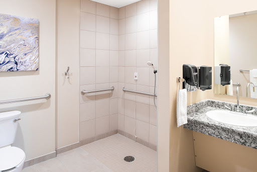 An accessible bathroom featuring a shower area with handrails and a sink.