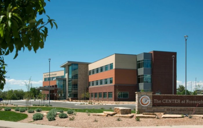 A modern office building with a landscaped entrance under a clear blue sky.