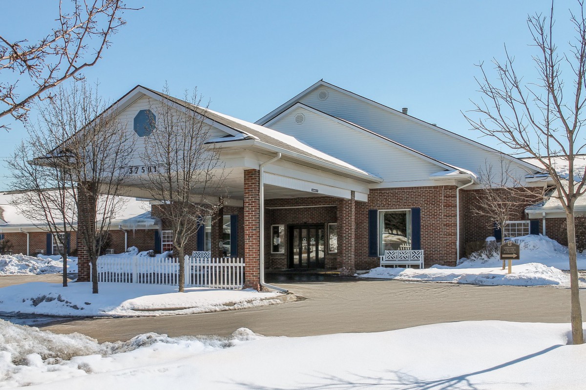 A winter scene featuring a building with a covered entrance, surrounded by snow.