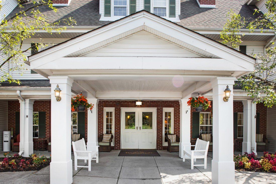 A welcoming porch entrance with white chairs and hanging flowers.