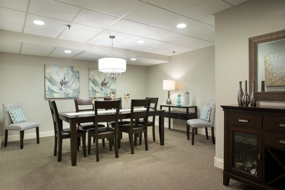 A well-lit dining room featuring a dark wooden table and chairs, with artwork on the walls and modern lighting.